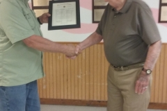 Commander Joe Rieke presents an award marking 60 consecutive years of membership in the American Legion to Post 27 member Robert Logel